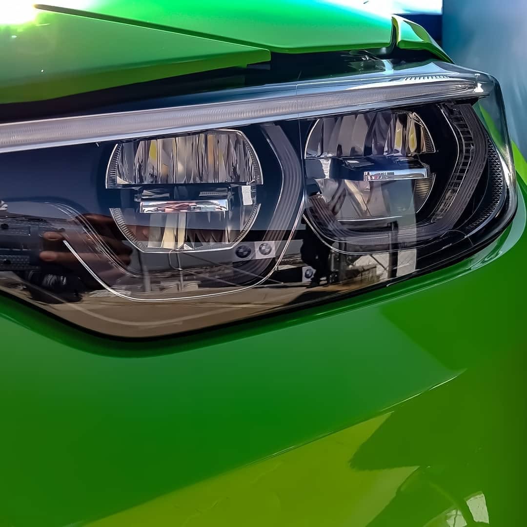 Close detail of the headlight on a bright green BMW coupe.
