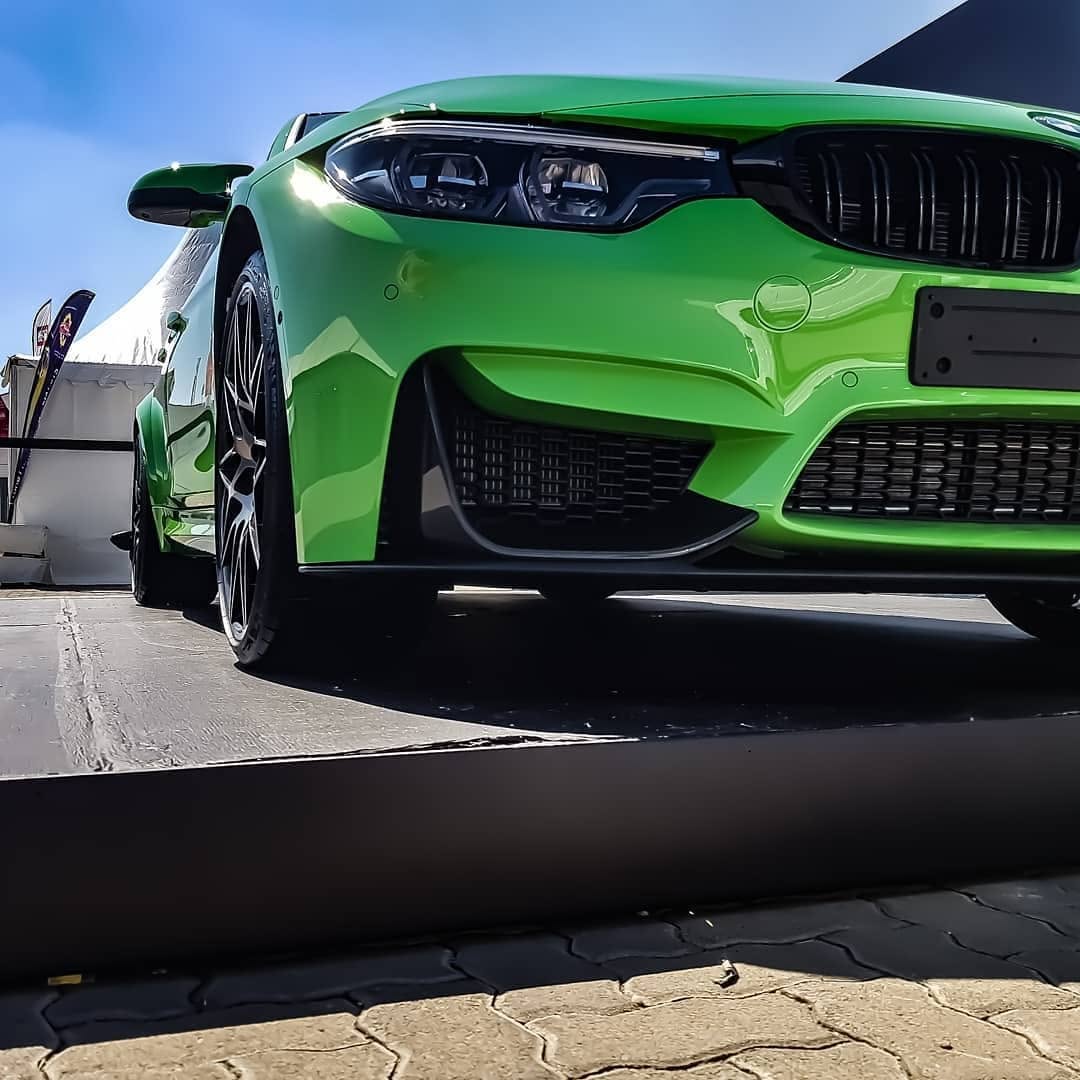A bright green BMW M4 shot low from the front at a motoring show.